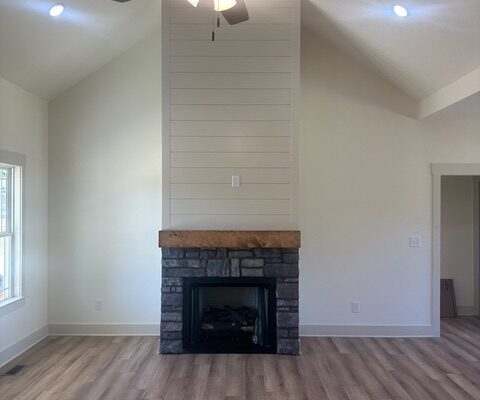 Stone fireplace with shiplap accent wall and vaulted ceiling in new construction home