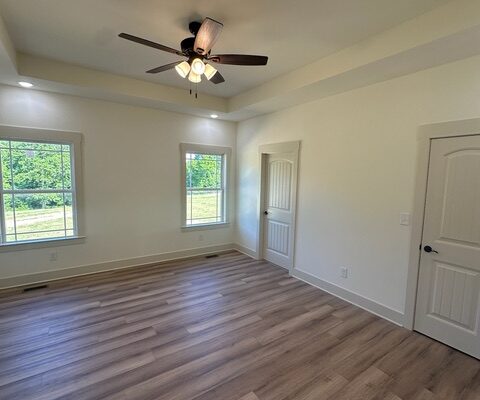 Bedroom with LVP flooring and tray ceiling in Liberty Road new construction home