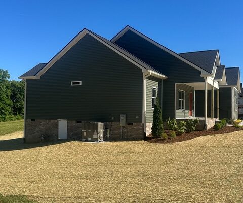 Side exterior of Charlotte, TN new construction home with gray siding and brick foundation