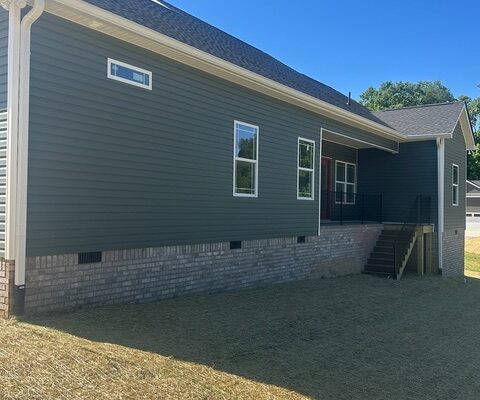 Rear side exterior of new construction home with covered porch and brick foundation
